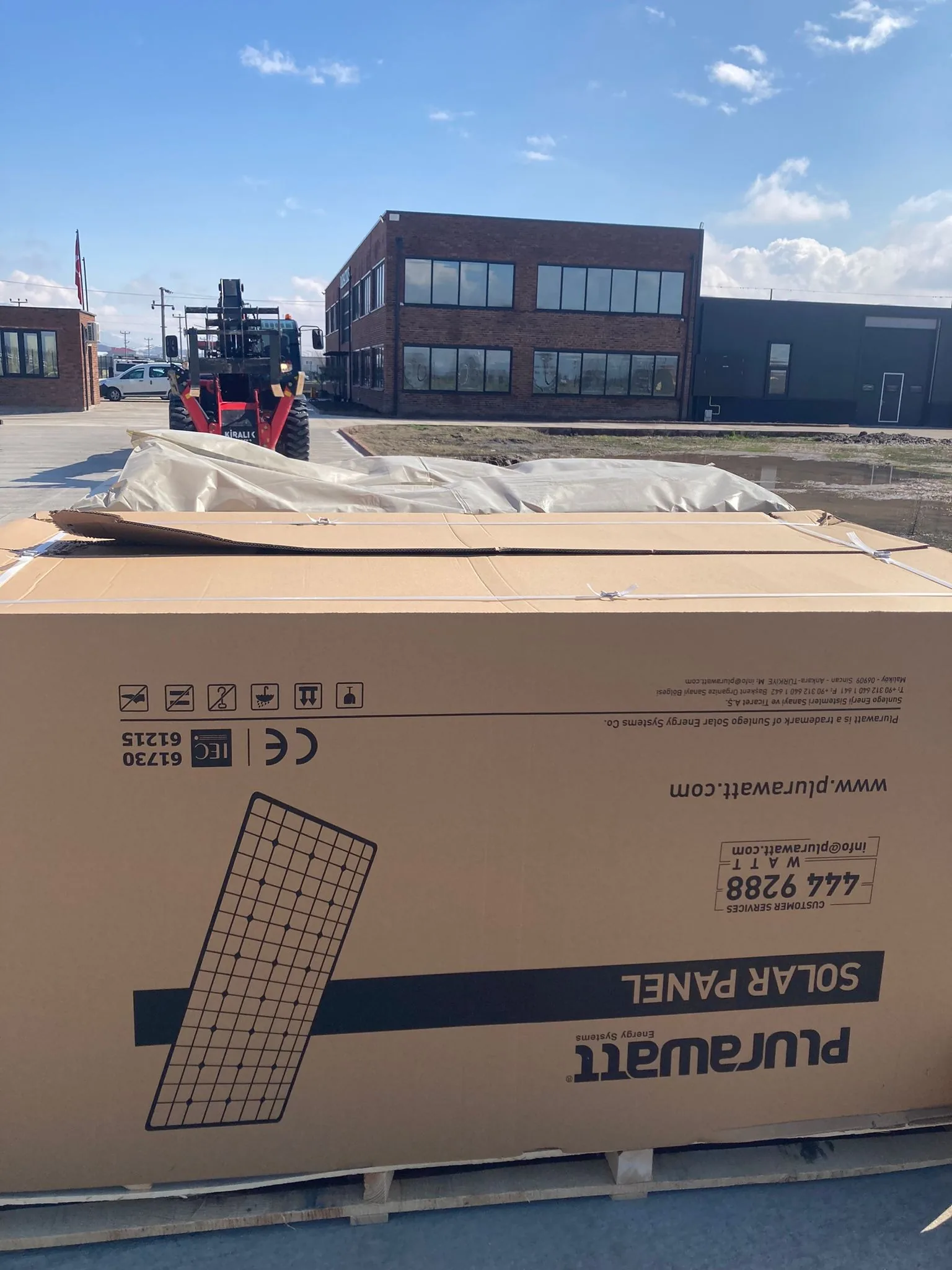Boxed solar panels delivered to the Erbaa factory yard in March 2022, the brick factory behind