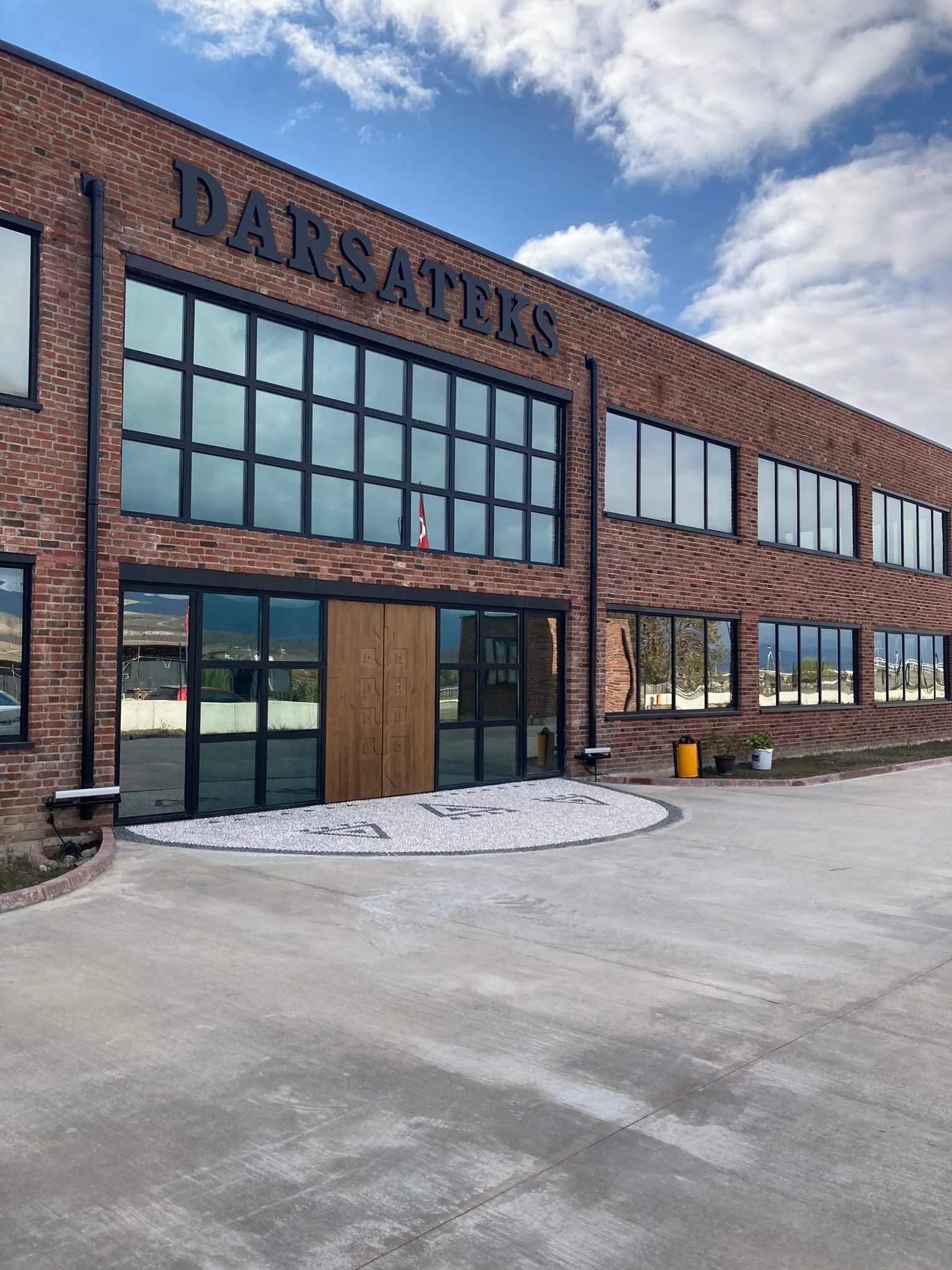 Entrance of the red-brick Darsateks factory in Erbaa, with the DARSATEKS sign above tall windows and wooden doors