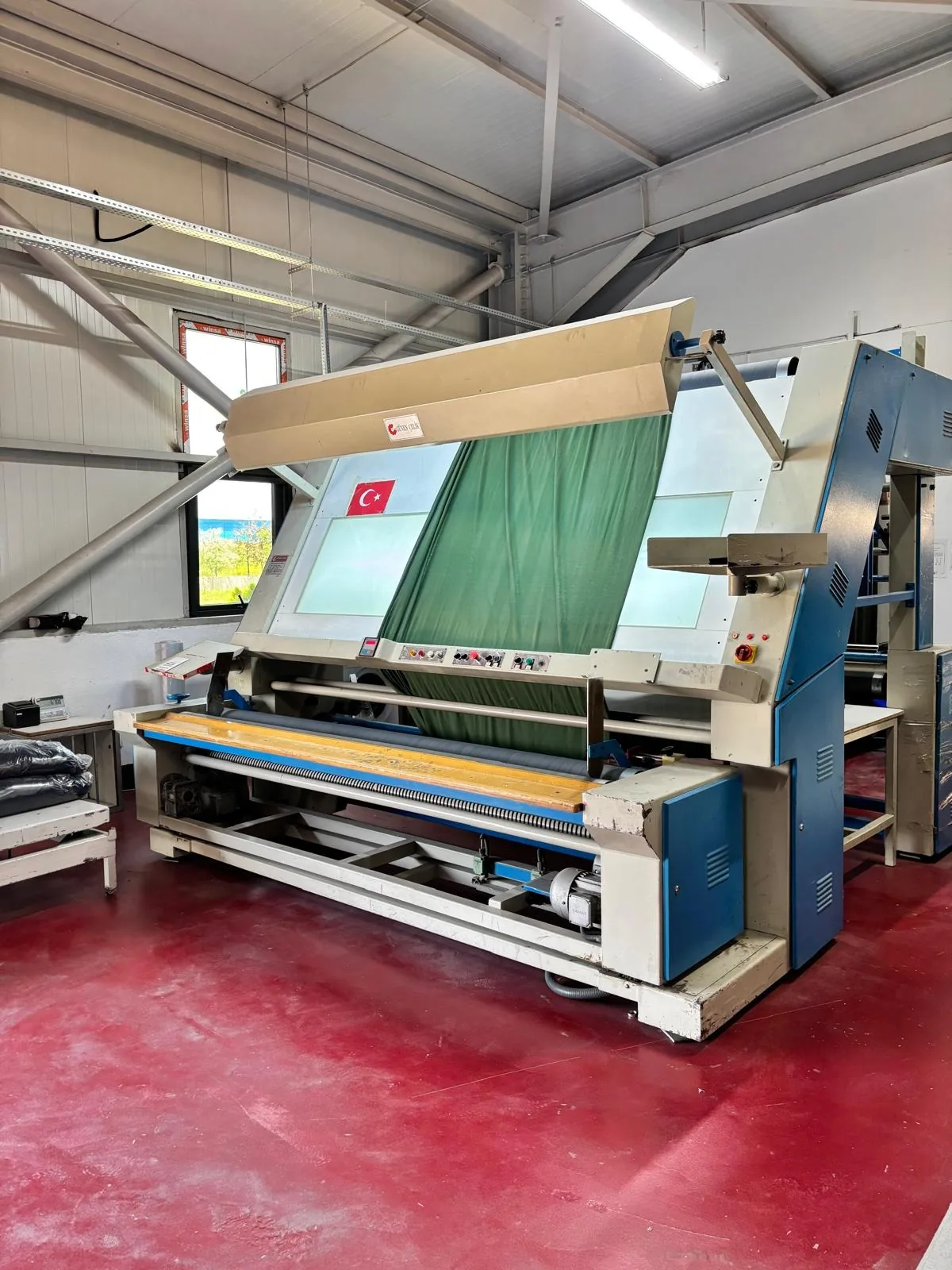 A roll of green fabric running over a lit inspection machine in the Erbaa factory