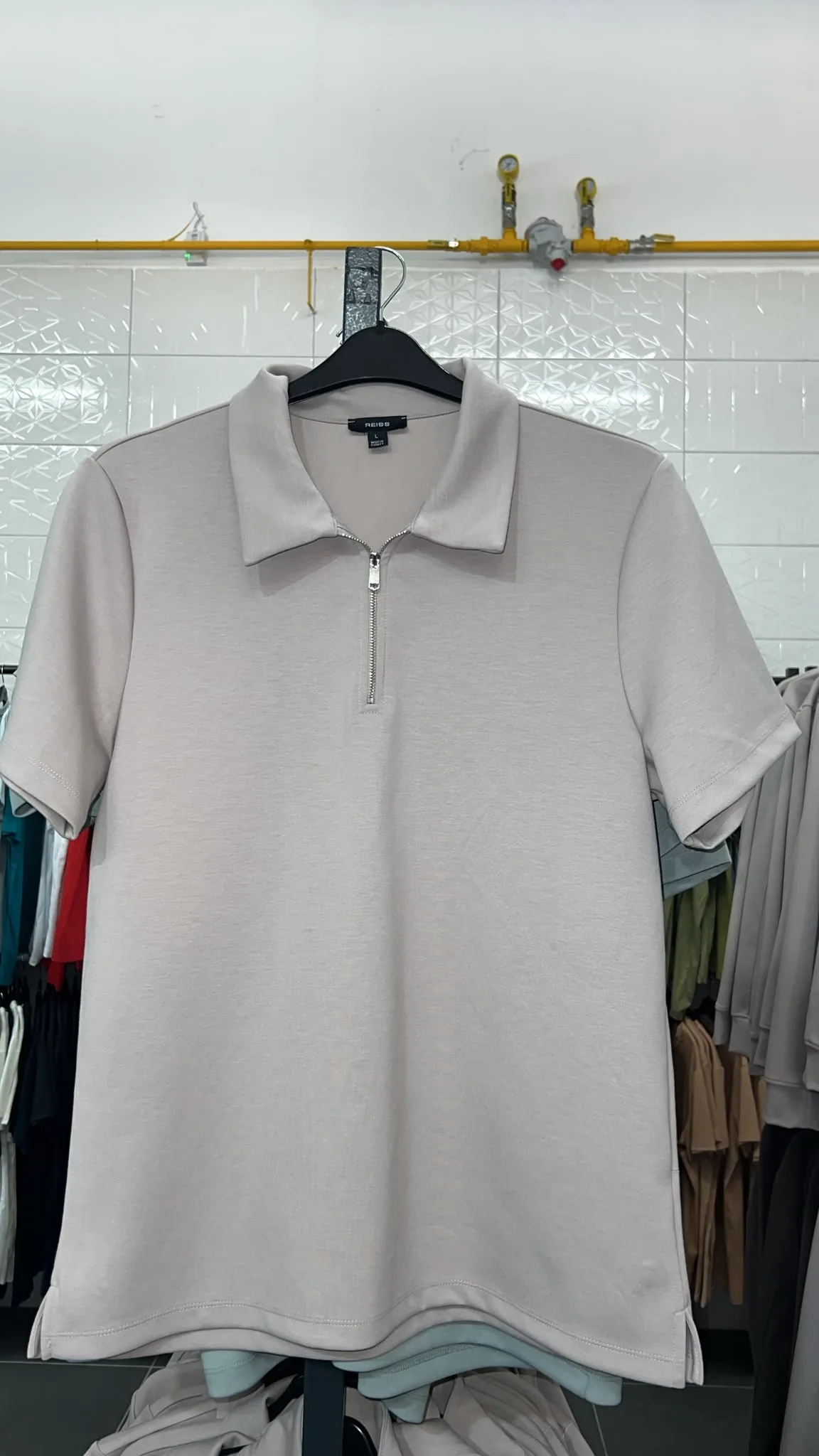 Grey knit polo sample with a zip neck hanging on a rail